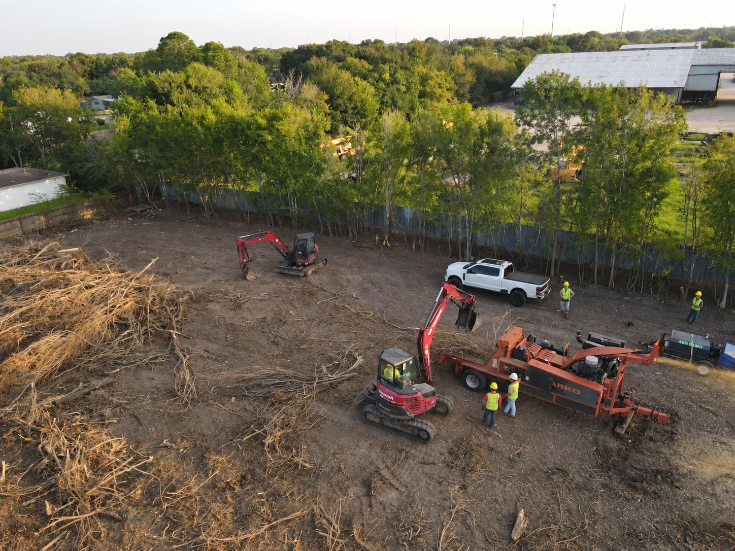 Aerial view of a 409 Demo land-clearing site with a whole-tree chipper and excavators